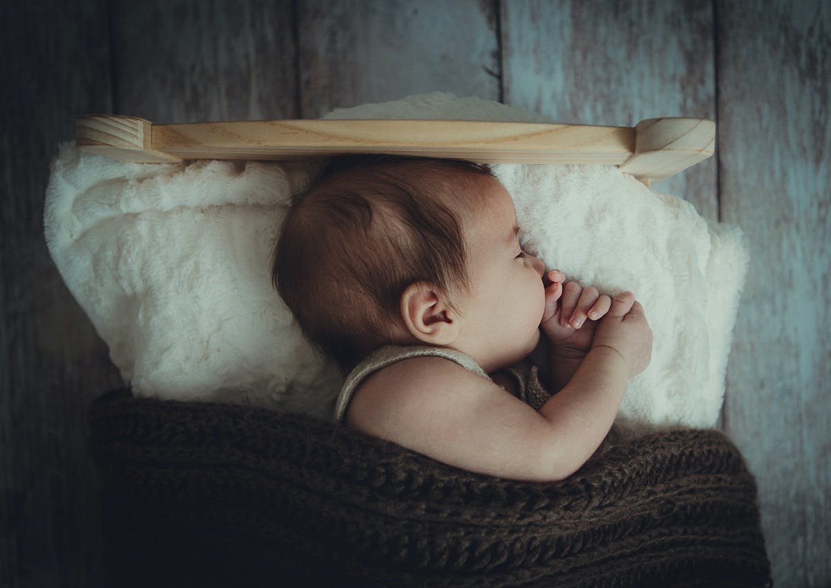 An eco baby sleeping in its hand built cot and knitted blanket