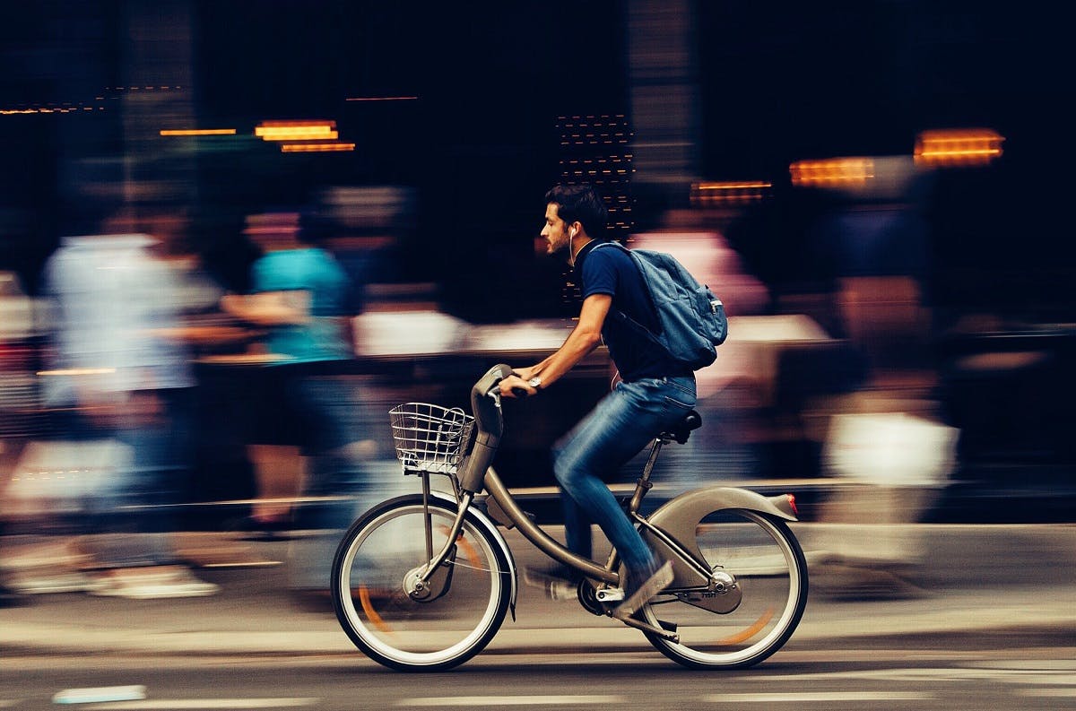 A man cycling through the city on an e-bike. E-bikes are at the forefront for the green commute.