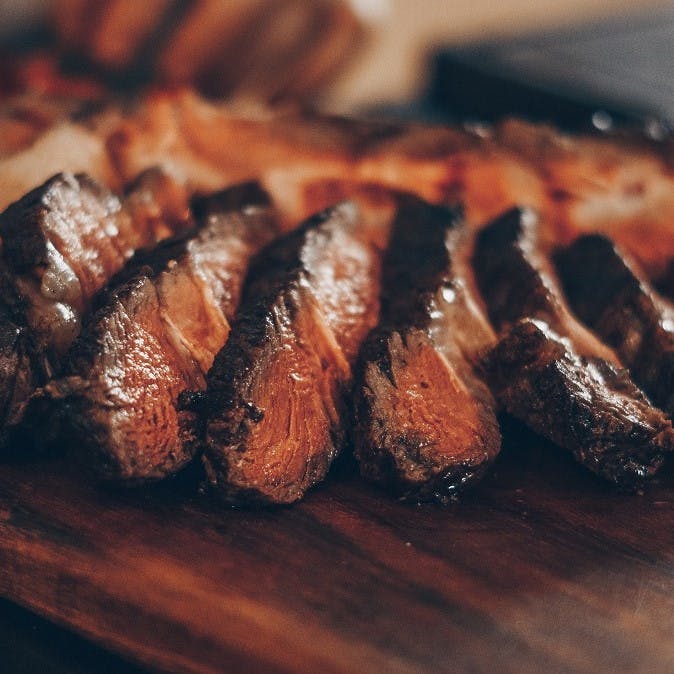 Slices of succulent steak on a wooden serving board. Cutting back on the consumption of such red meat dishes will significantly reduce your CO2 footprint.