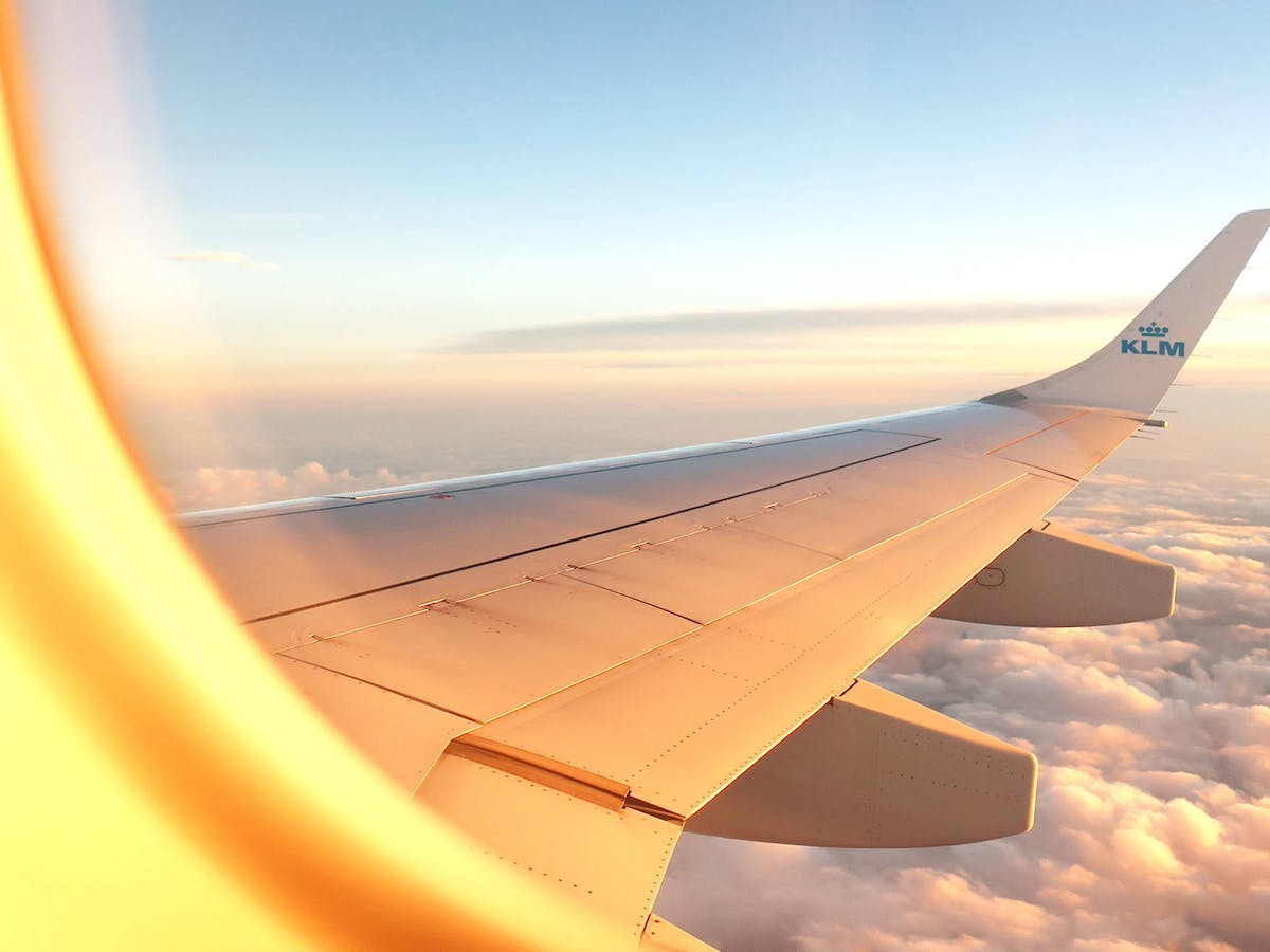A view of the wing of an airplane through the window as it glides over white clouds