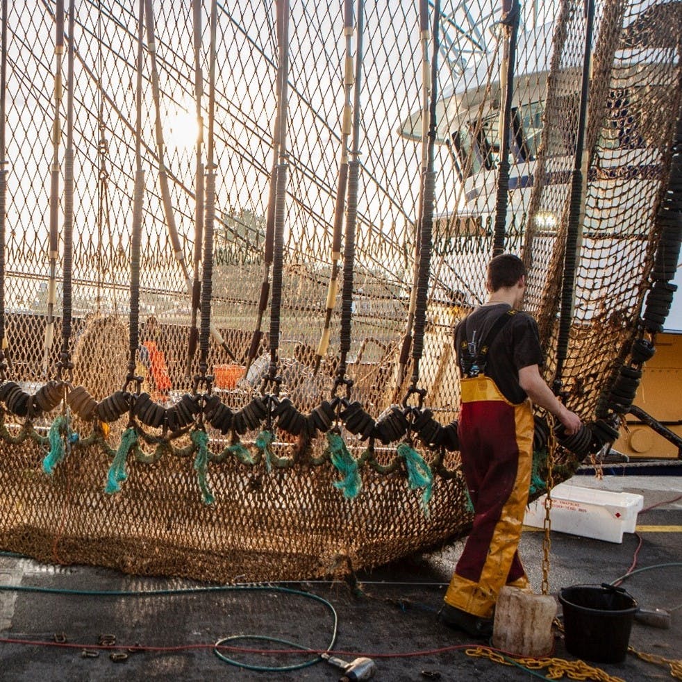 A fisherman works on a fishing net.
