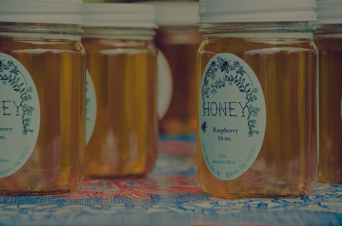 Jars of local raspberry honey on display. Local honey is the epitome of eating seasonally and local.