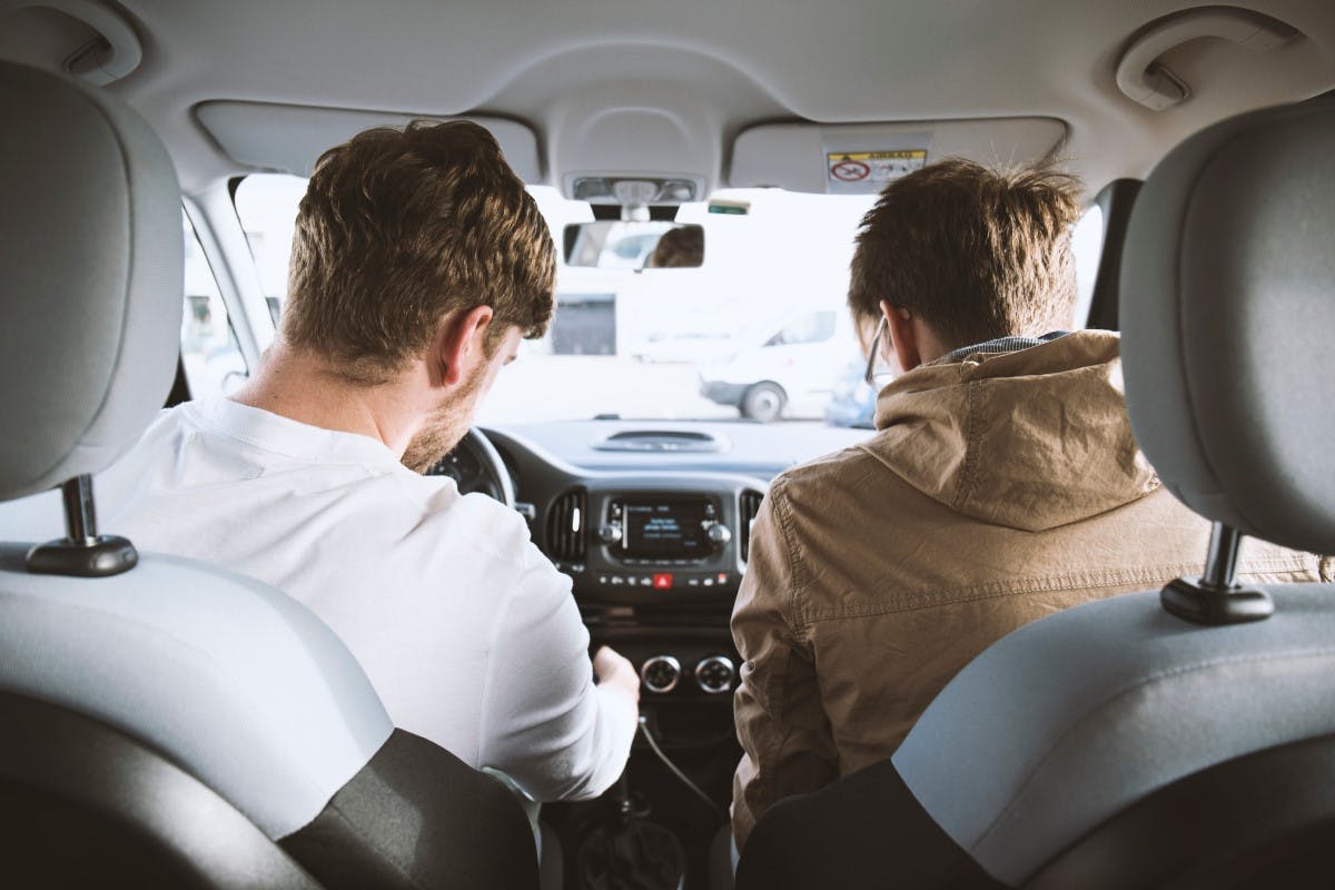 A driver and a passenger as seen from the back seat of a car.