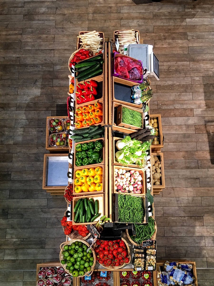 An aisle of fresh, colourful, local vegetables in an organic fruit and vegetable shop. 