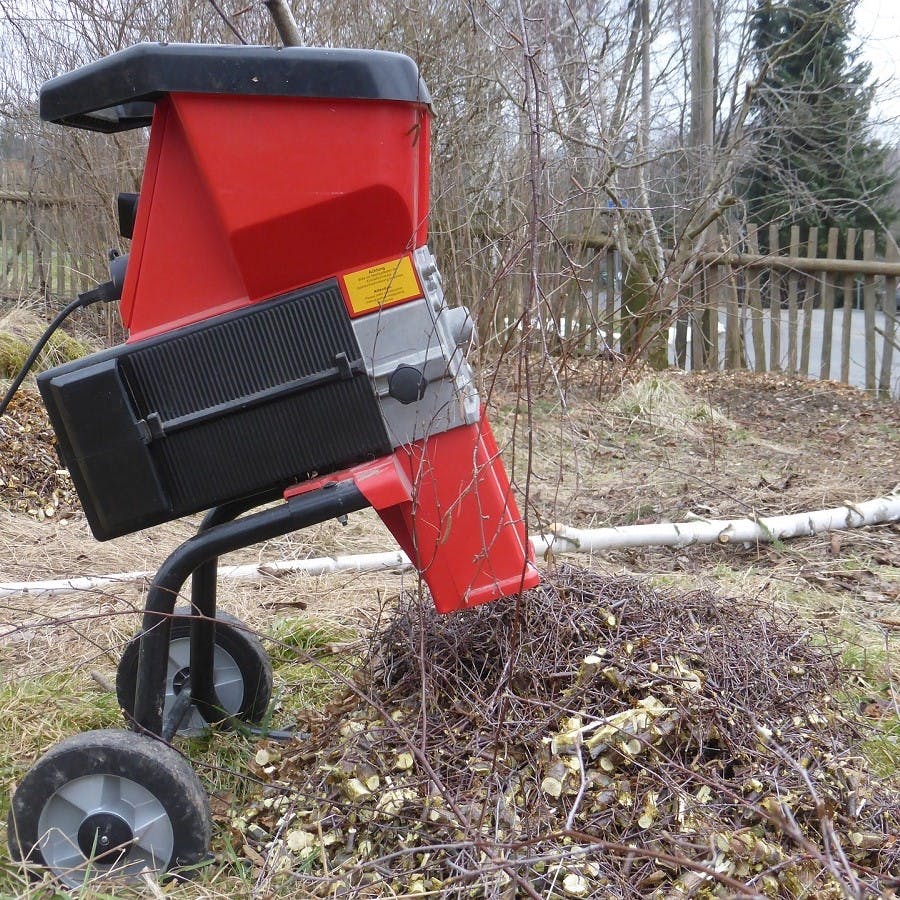 An electric shredder chopping up garden waste. Shredding your brown material will help speed up the home composting process.