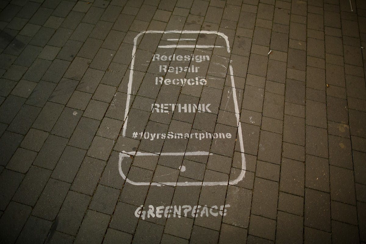 A graffiti image on a city street asking us to redesign, repair, recycle and recycle are smartphones so they can become more sustainable and ethical in the future.