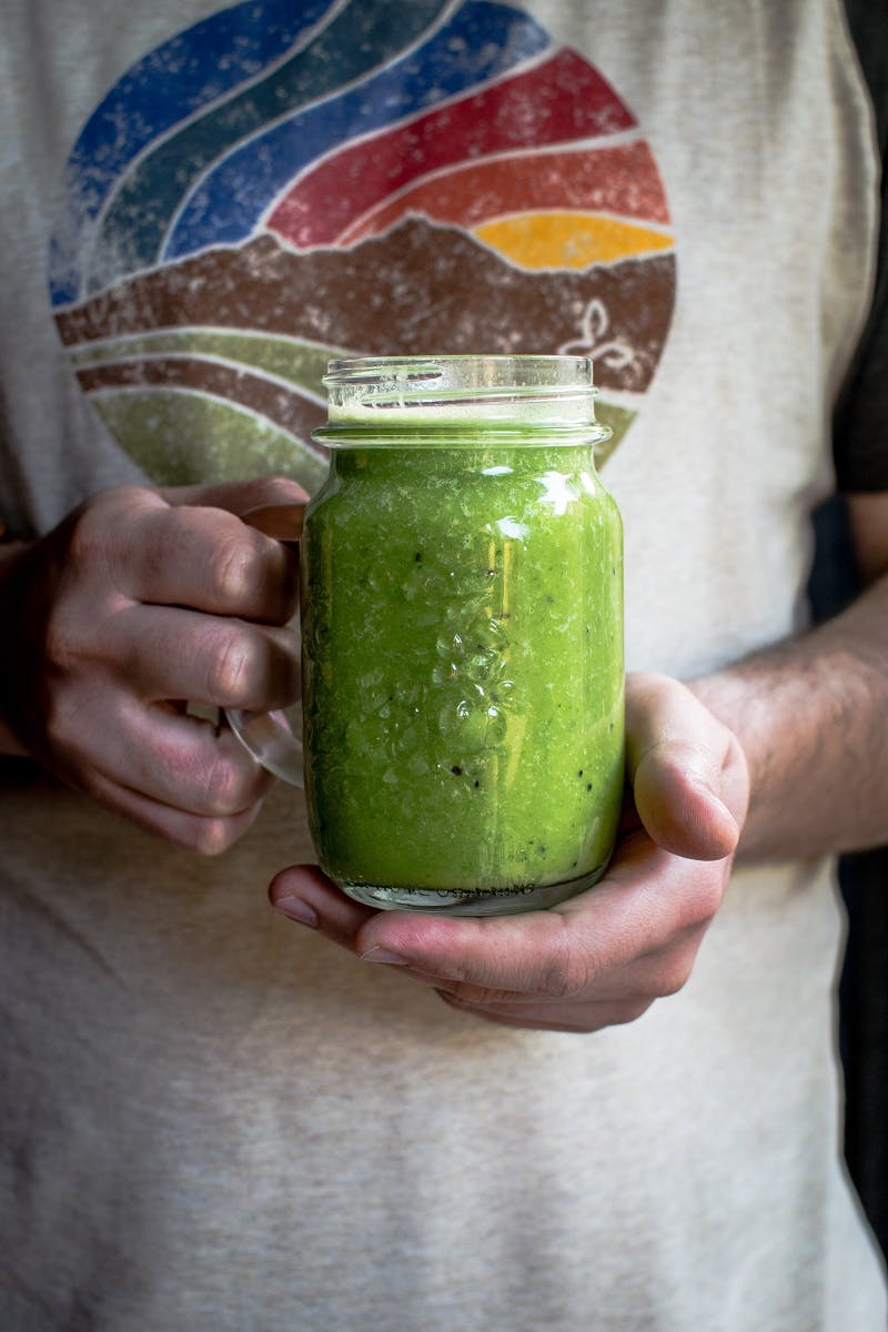 A person holding an edible insect green smoothie. 
