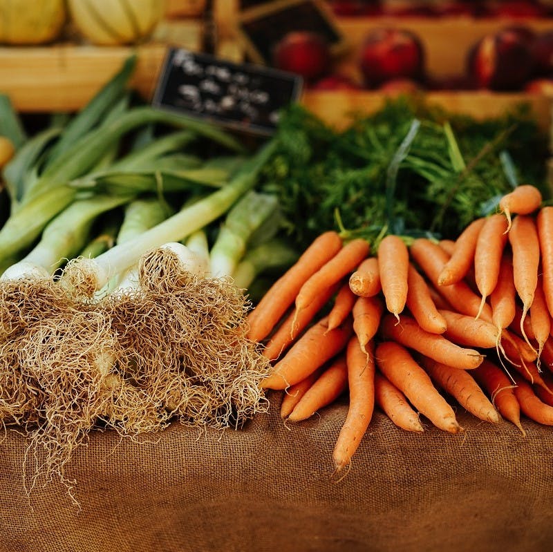 Organic leaks and carrots on sale at a farmers' market. To eat seasonally and locally helps your local farmer. 