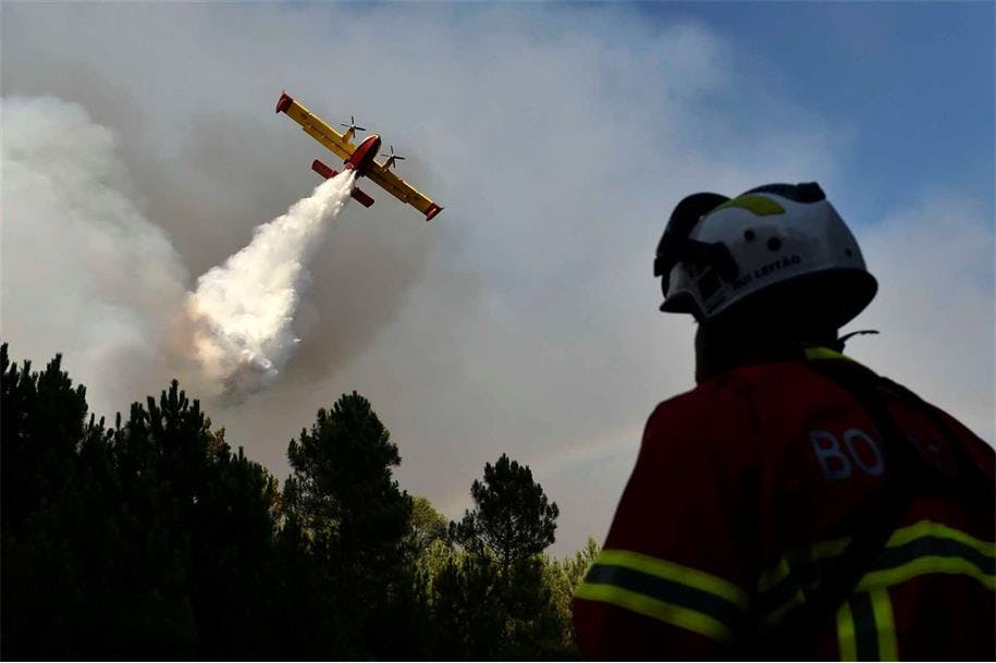 A plane drops water over a forest fire in Portugal.