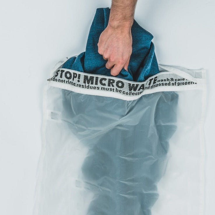 A person putting a towel inside a Guppy Bag. Another essential accessory for living plastic free. 