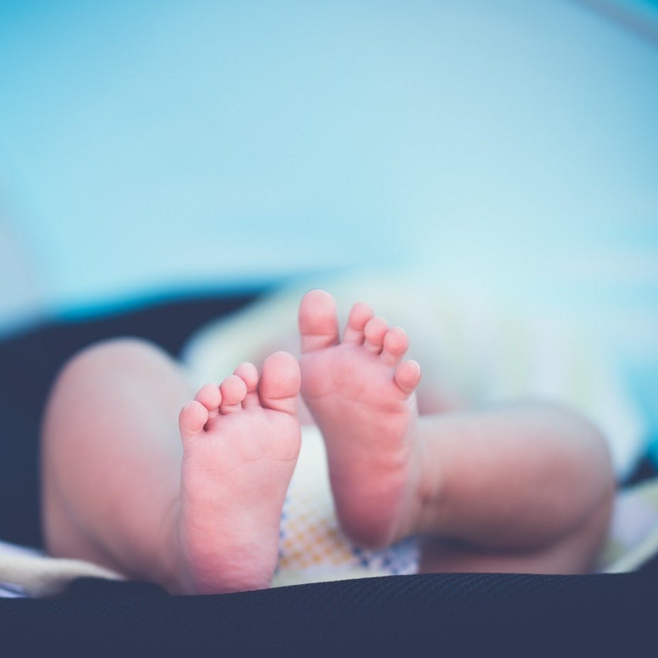 A happy baby on their back dressed in a fabric nappy. Babies are said to be more comfortable in cloth nappies. Another plus for reusable nappies vs disposable.  