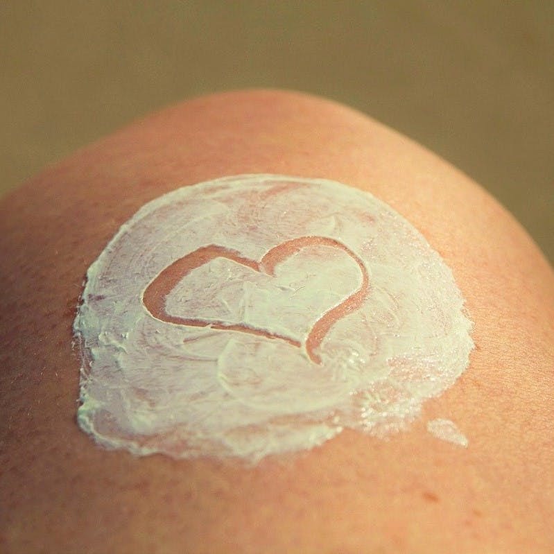 A patch of sunblock on someone's knee with a heart shape drawn into it. 