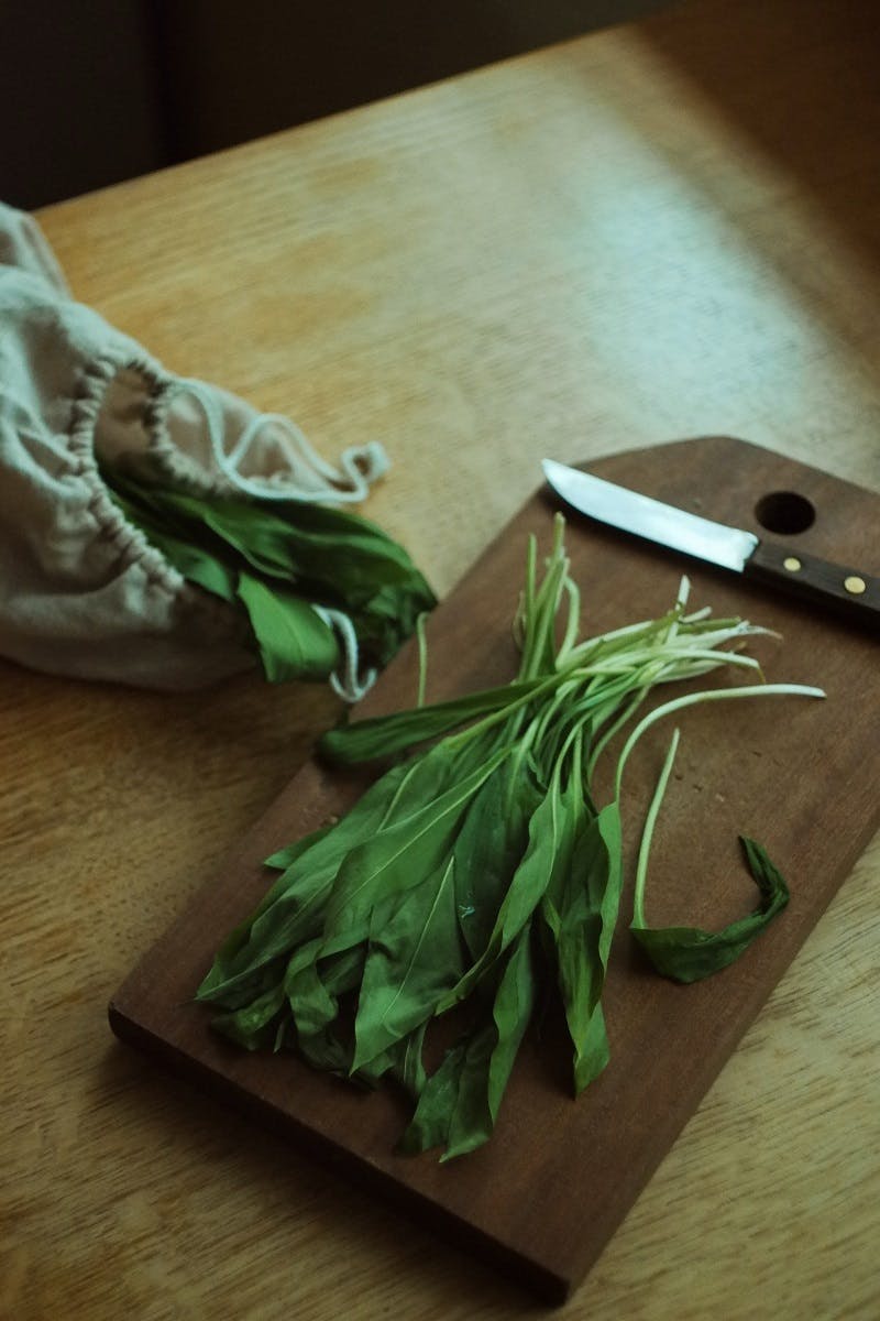 Freshly foraged wild garlic on a chopping board next to a knife.