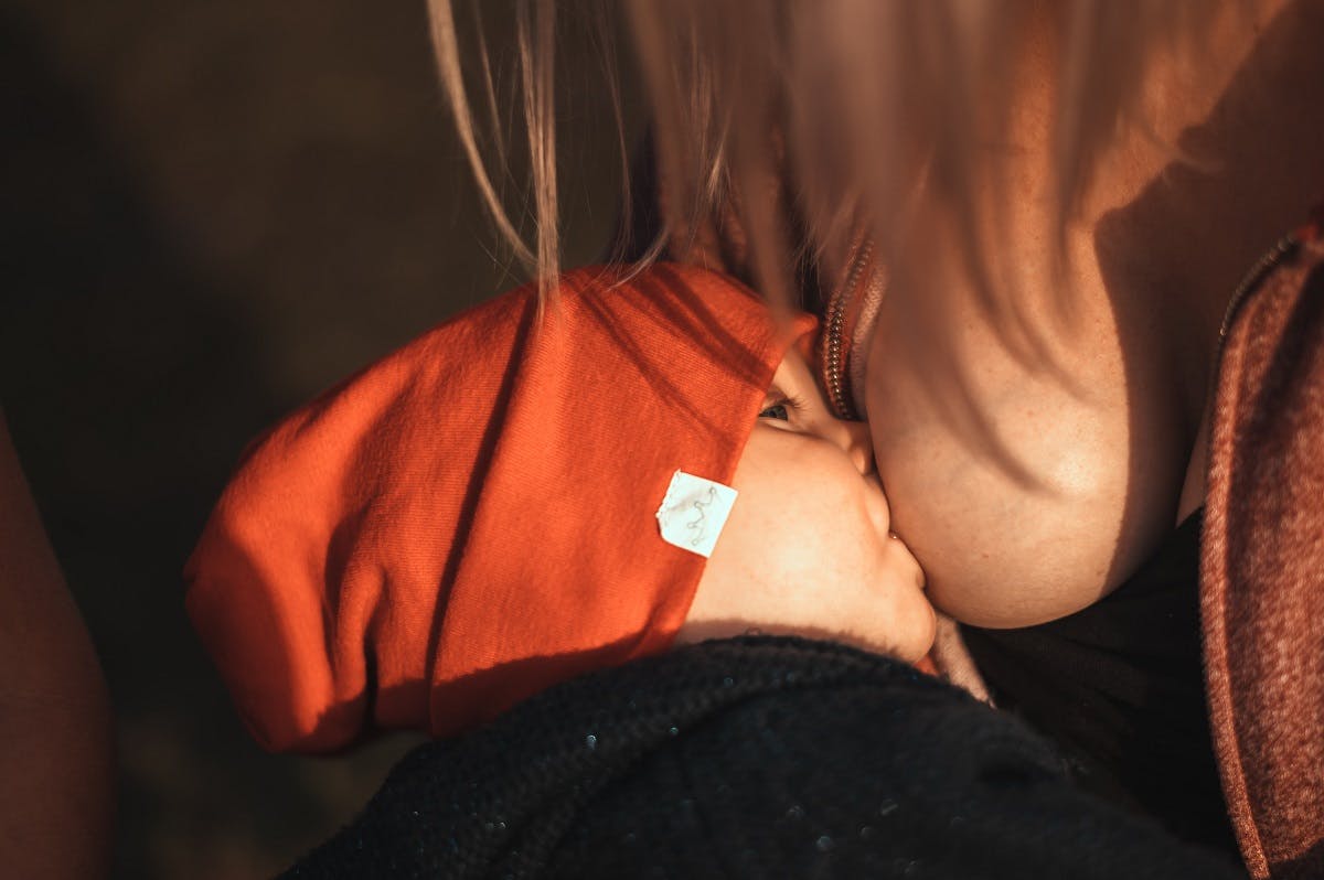 A mother breast feeding her young baby. There are clear environmental benefits for breast feeding include saving the energy and resources of producing formula milk. Breast feeding is just one of many ways in raising an eco baby.