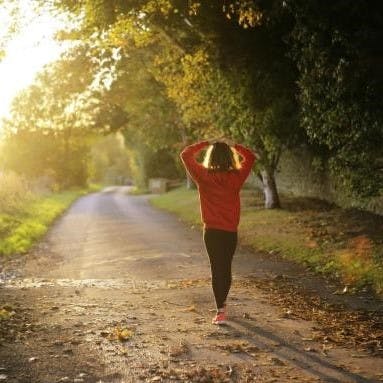 A woman takes a walk in a green space in a city.