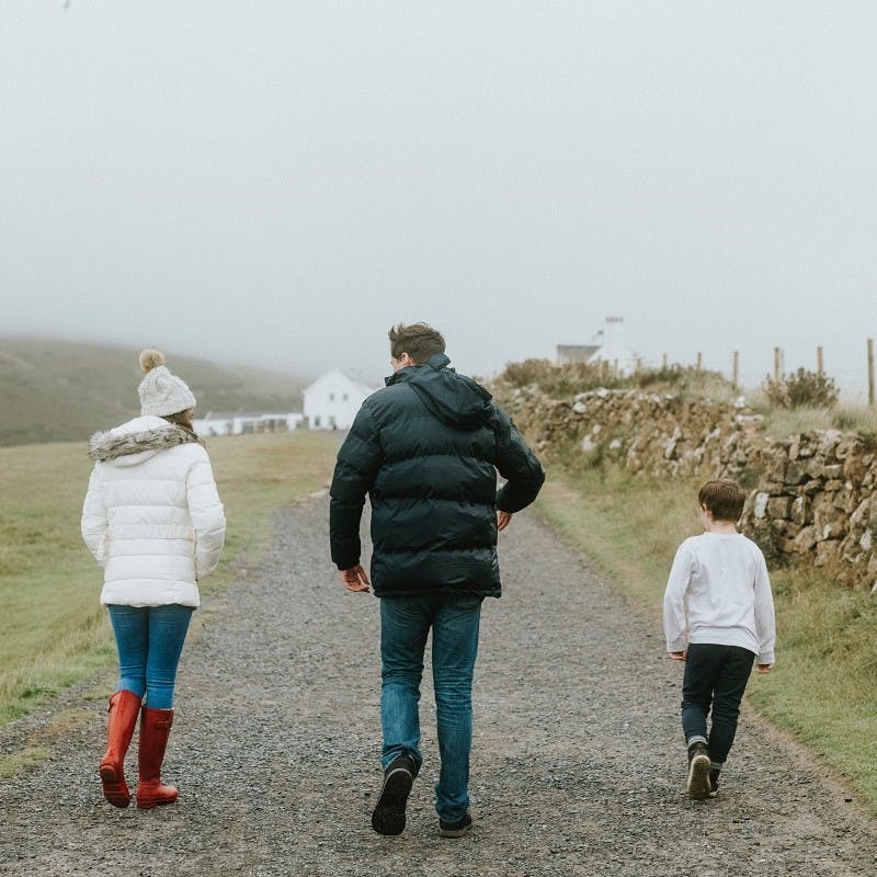 A father walks with his two children through some farmland on a misty day. Having more time with your family is just one of the many advantages of working from home.