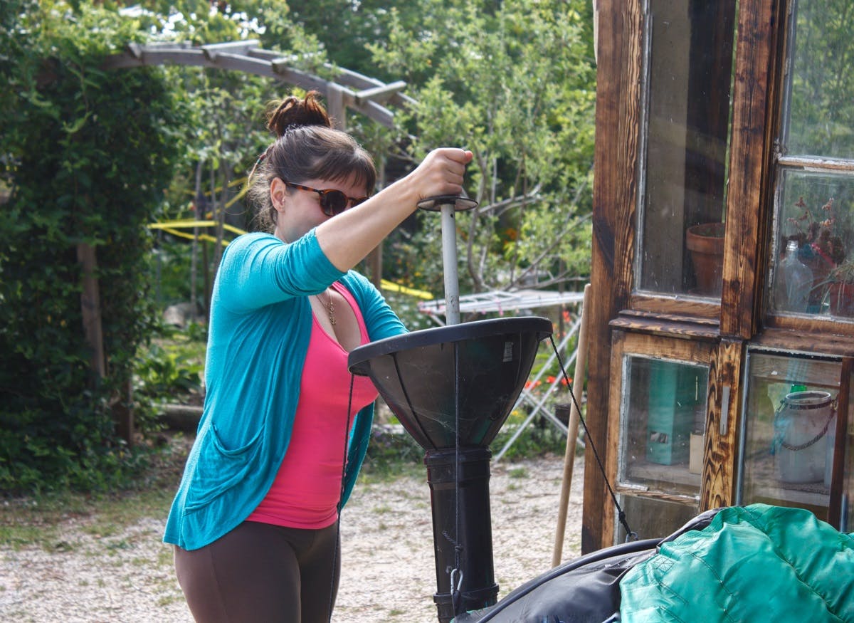 A lady putting food waste into her Home Biodigester 