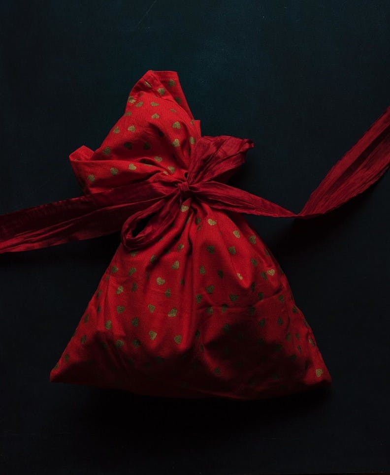 A red and golden starred fabric gift wrap bag. Wrapping gifts in such a bag is a easy first step toward sustainable Christmas gifts. 
