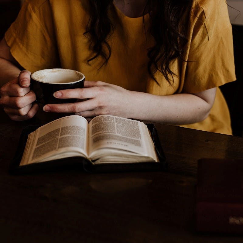 A lady reading a book with a coffee. Enjoying simple pleasures is at the heart of slow living. 