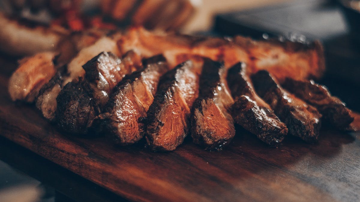 Slices of succulent steak on a wooden serving board.