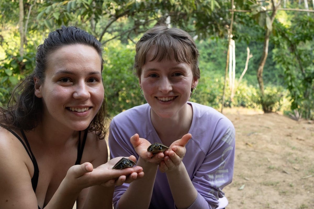 Adriana and Morgan holding baby turtles in the jungle