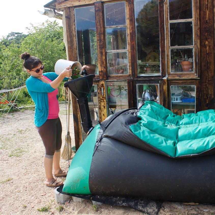 A lady putting food scraps into a homebiogas home biodigester. 