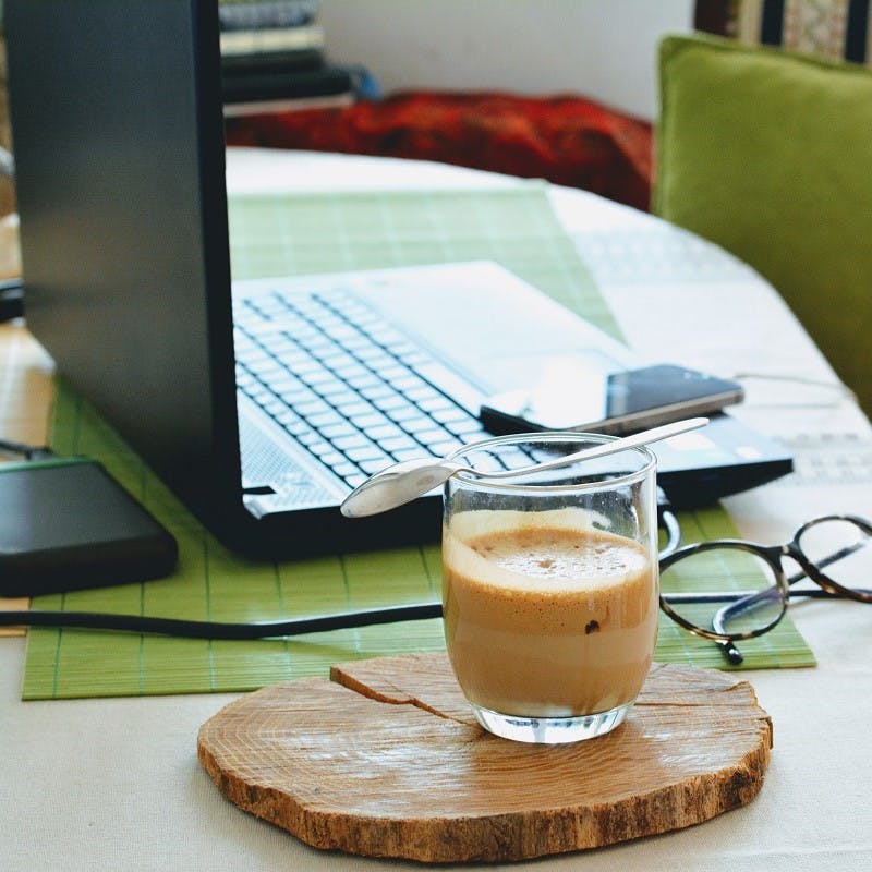 A work from home office complete with laptop, mobile, glasses and a fresh coffee. Instead of a green commute, eliminate the commute by working from home.