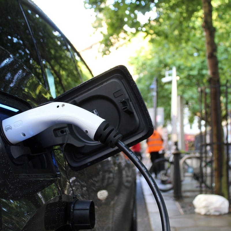 An electric car charging by the side of an urban street.  Convenience of charging vs infrastructure of charging is just one of the many electric cars pros and cons debate. 