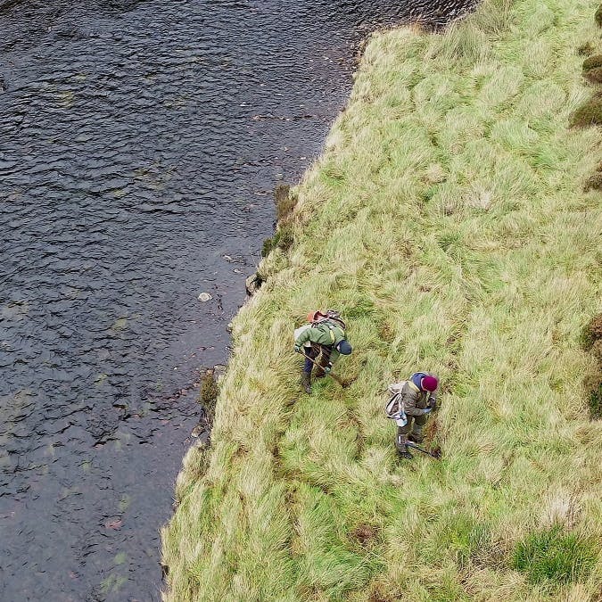 Tree planters working alongside a riverbank in the Scottish Highlands.