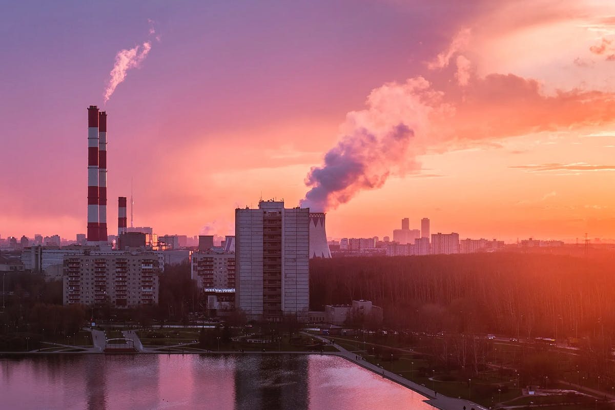 Factory releasing gases into the atmosphere at sunset.