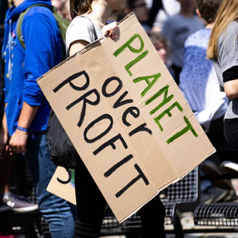 A Planet for Profit sign held up during a protest. 