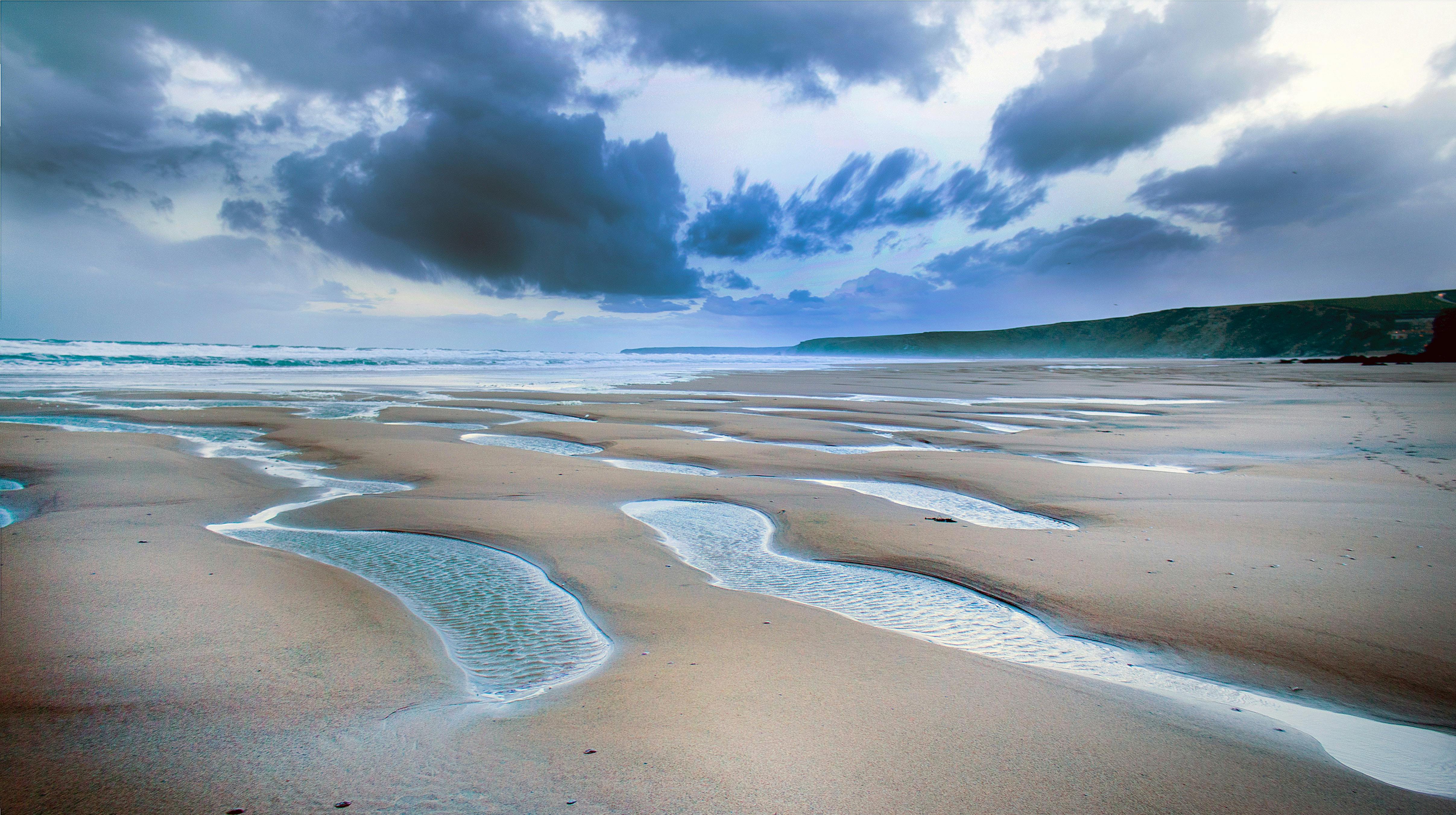 A beach at low tide with dark clouds overhead