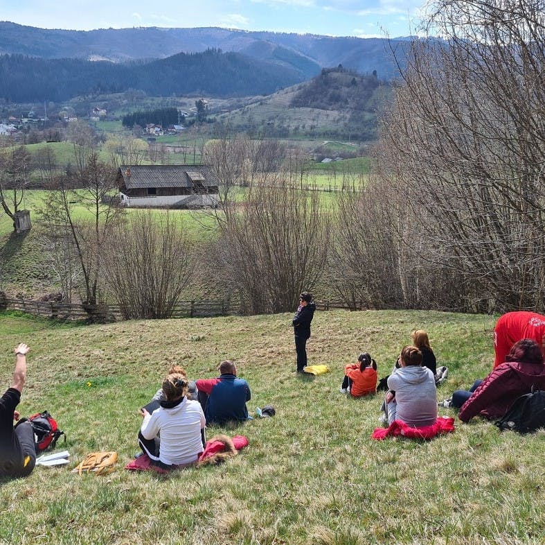 A nature-based educator and her students in a field.