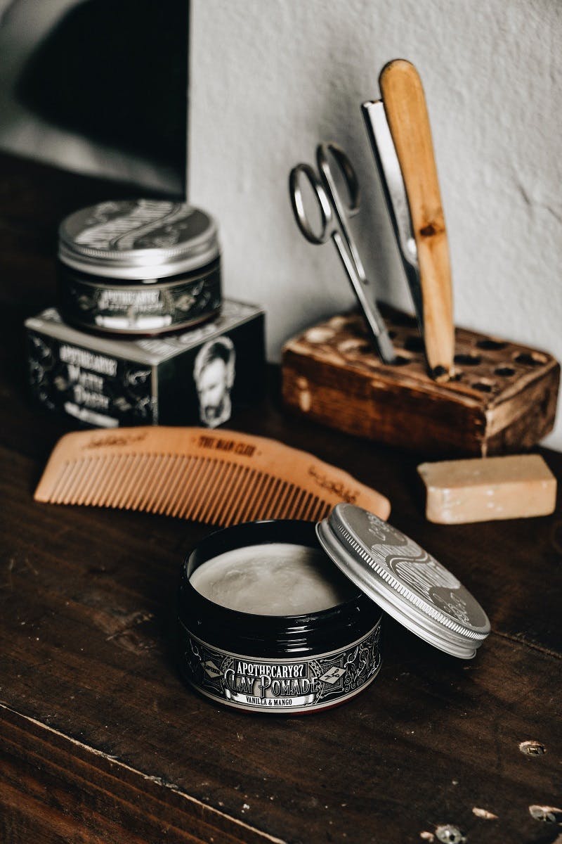 A cut throat razer, barber's scissors and solid bar of shaving balm on a shelf at a barber's shop. 