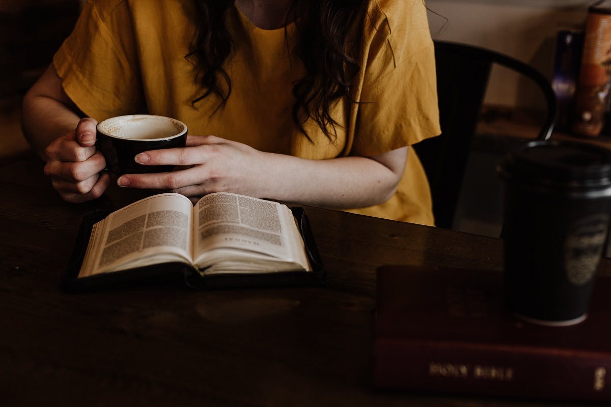 A lady reading a book with a coffee. Enjoying simple pleasures is at the heart of slow living.