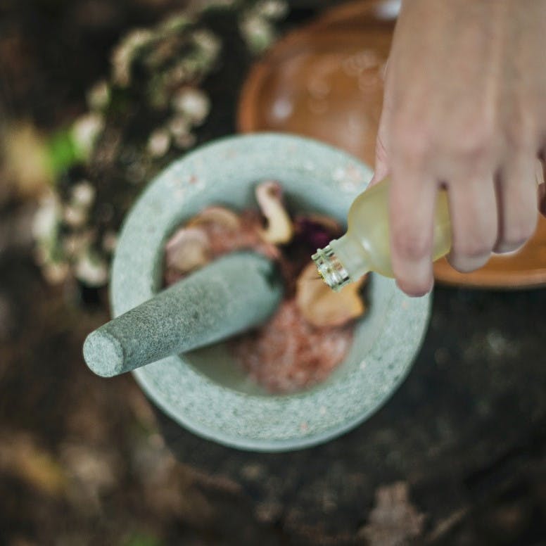 A lady using a pestle and mortar to create her own sustainable makeup and other eco friendly cosmetics.