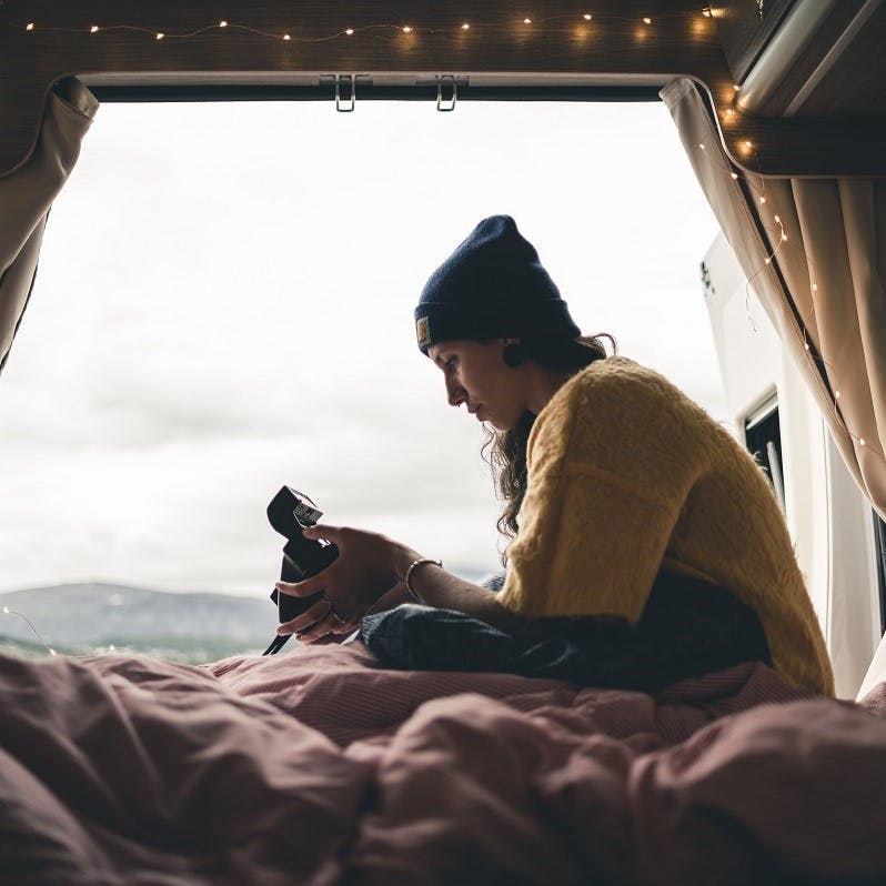 A girl playing with her camera in the back of her camping car