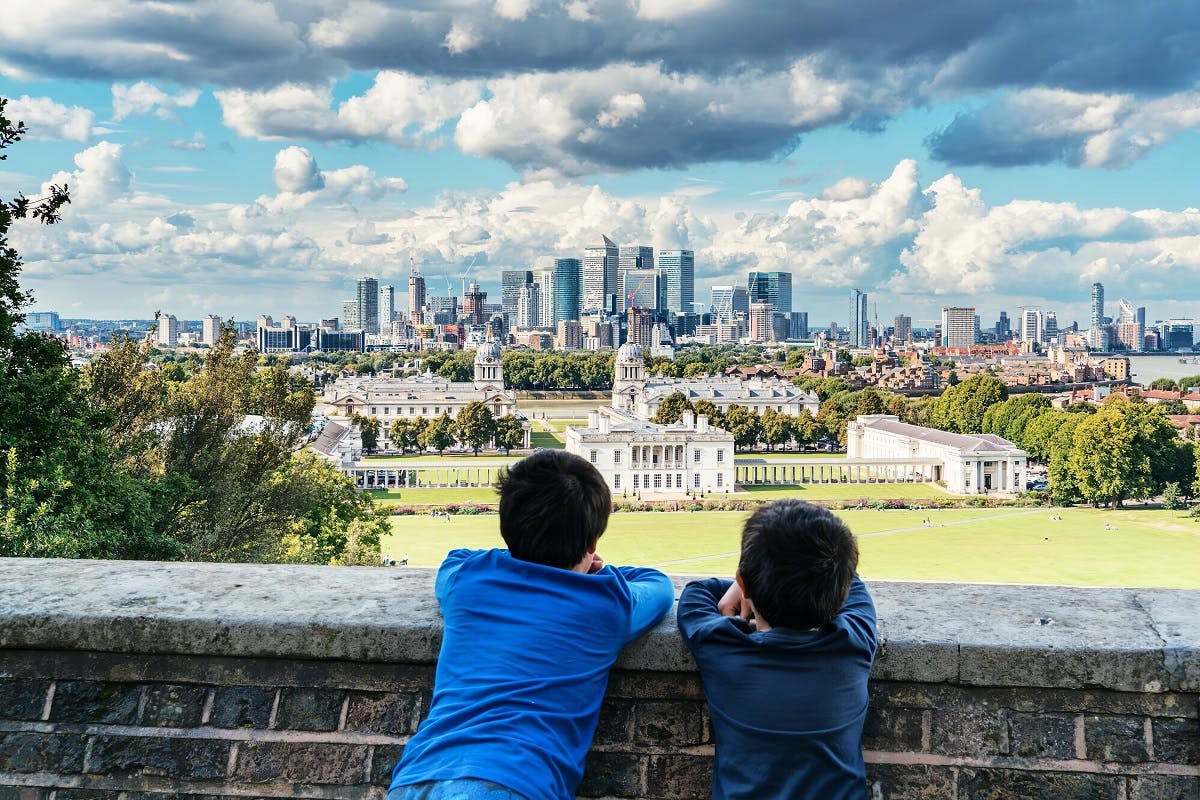 Two boys look over a wall towards the city of London.