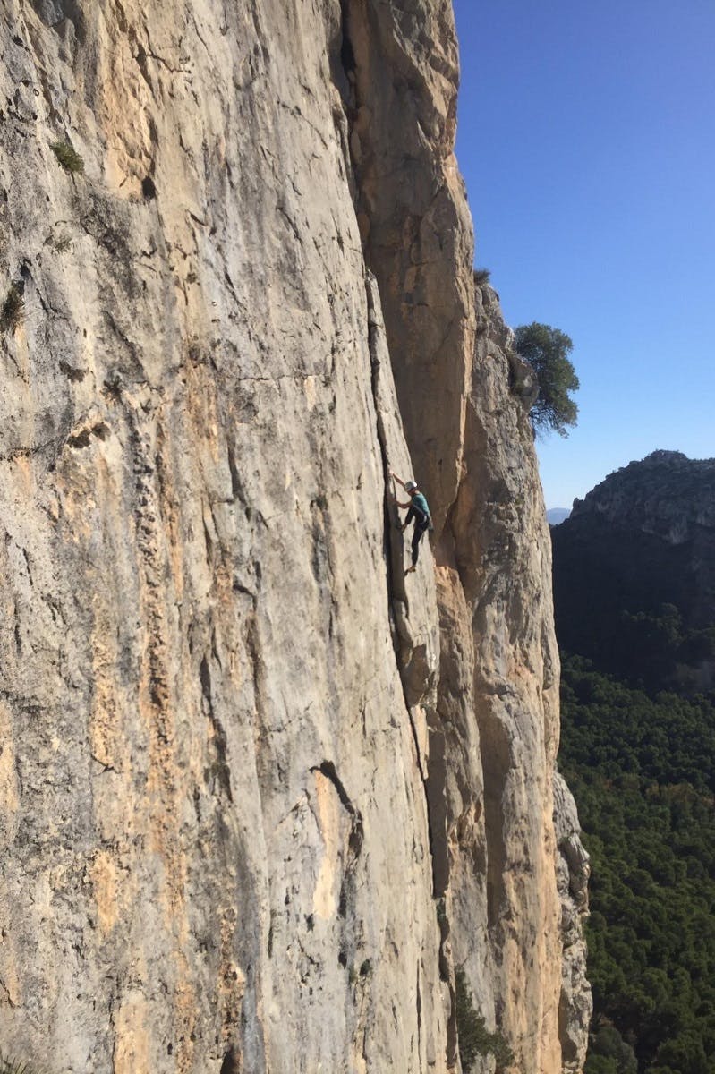 Rock climber using a crack in the rock to ascend a limestone cliff.