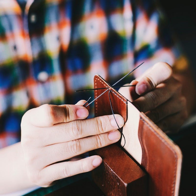 A person repairing a leather wallet
