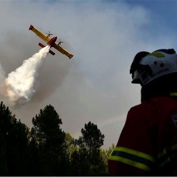 A plane drops water over a forest fire in Portugal.