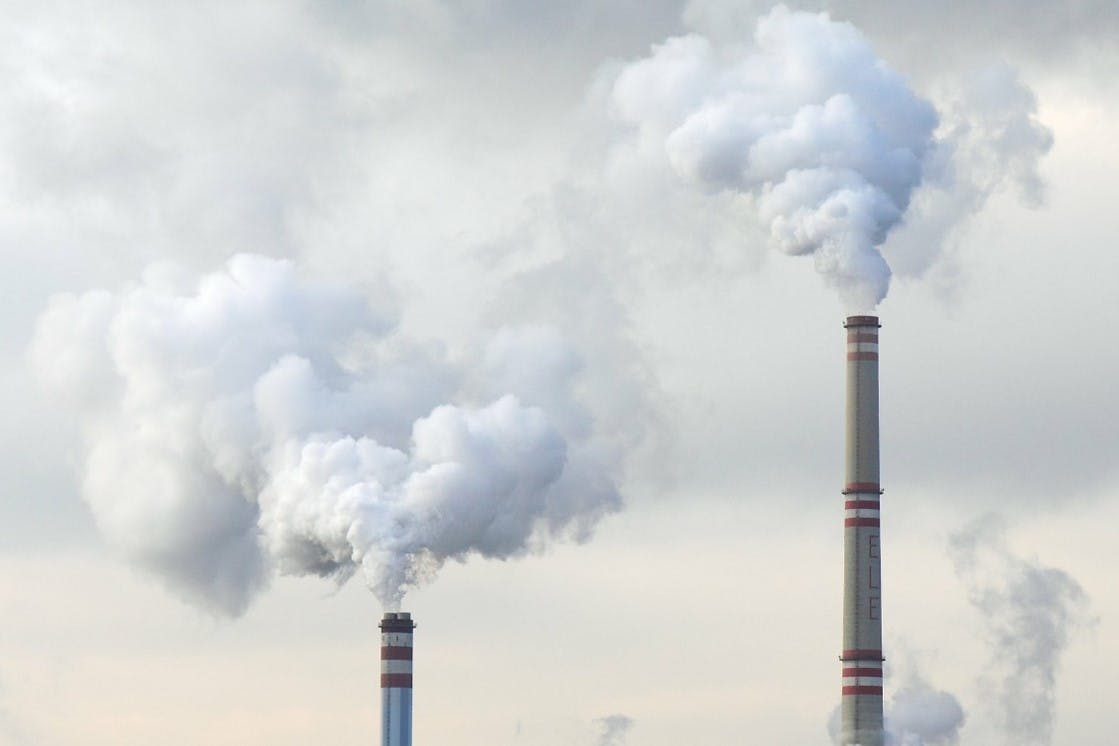 Two factory chimneys pumping CO2 into the atmosphere. An imbalance of CO2 in the atmosphere causes climate change