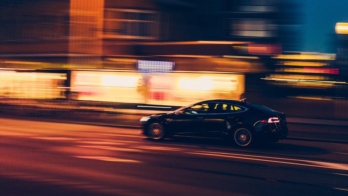 A black hybrid car whizzing through a town centre