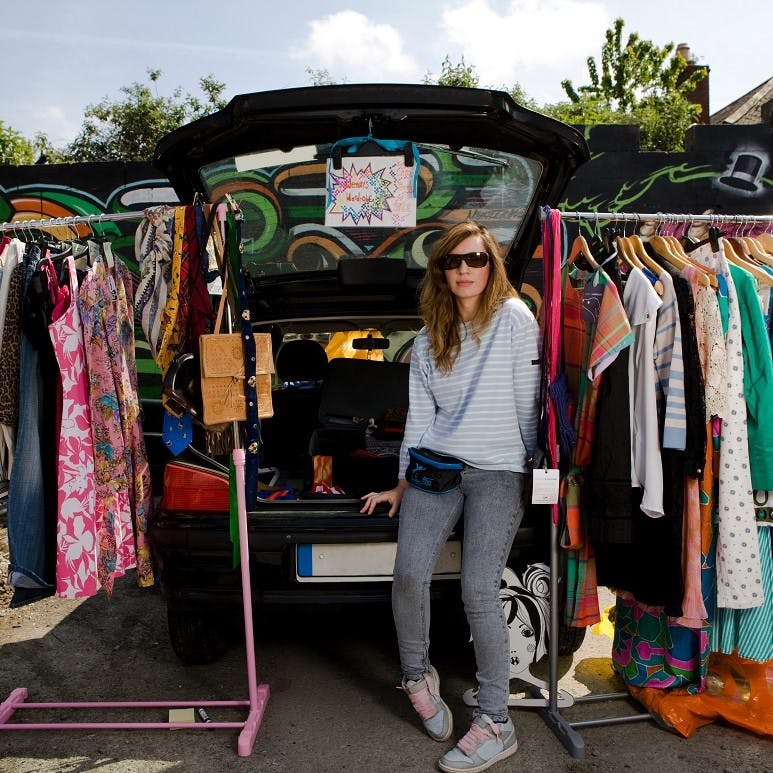 A girl getting rid of her second hand clothes at a car boot sale 