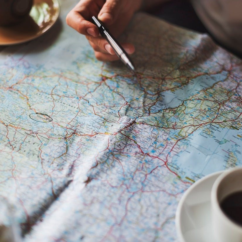 People poring over a road map with pen and coffee