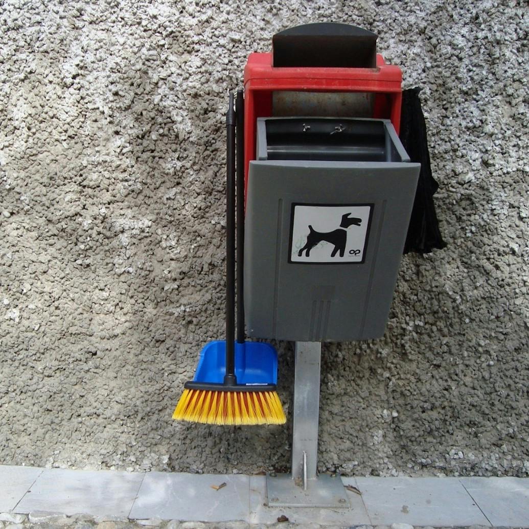 A dog poo bin complete with bags, a dust pan and brush.