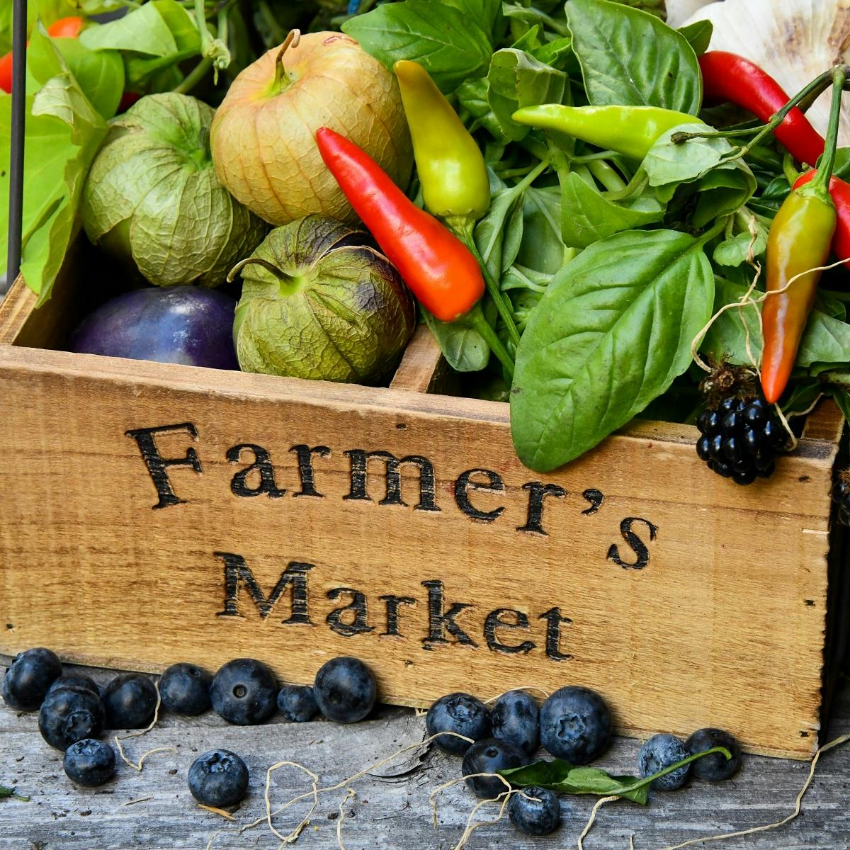 Wooden box with the words "Farmer's market" written on it and filled vegetables 