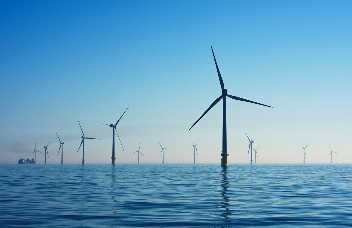 A line of wind turbines in the ocean.