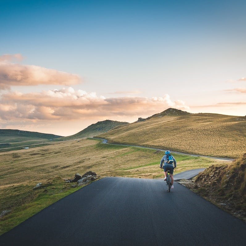 A person on a cycling adventure through the peak district. Find what you love and do more of it is the slow living moto