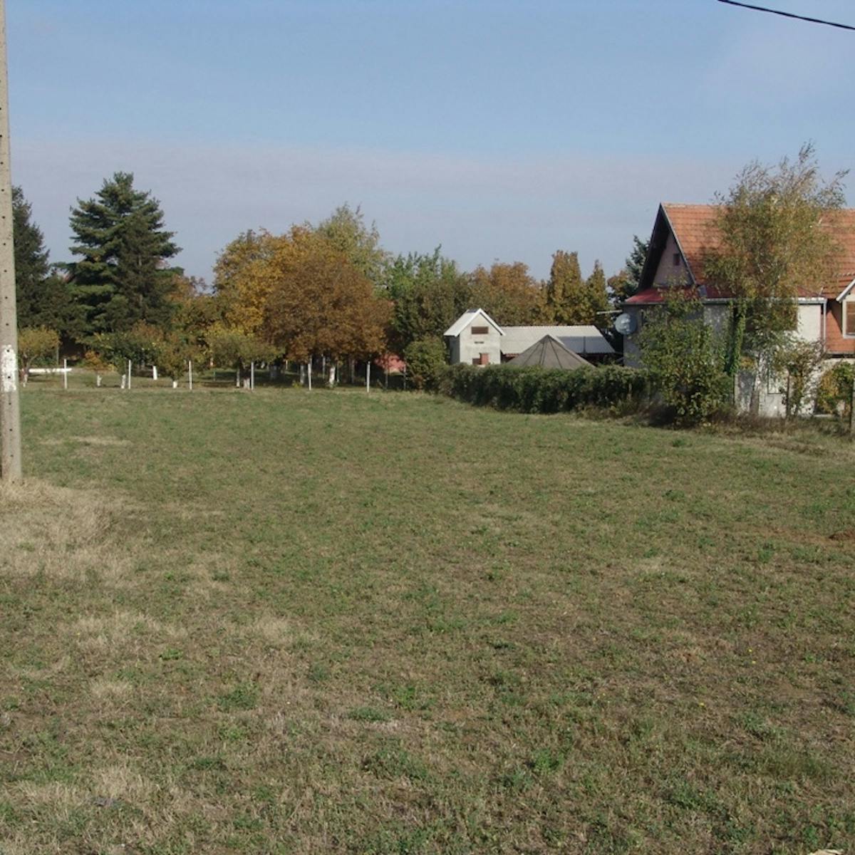 an empty grass field with a house beside it